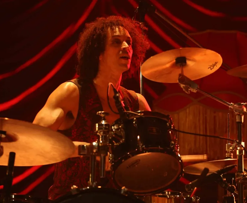 Zack playing drums in dim, red lighting.